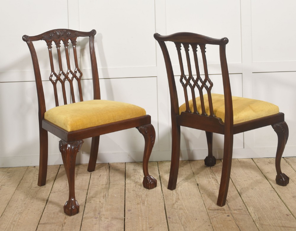 Set of four dark mahogany dining chairs featuring carved pierced splats, yellow velvet upholstered seats, and cabriole front legs with ball and claw feet. View IV
