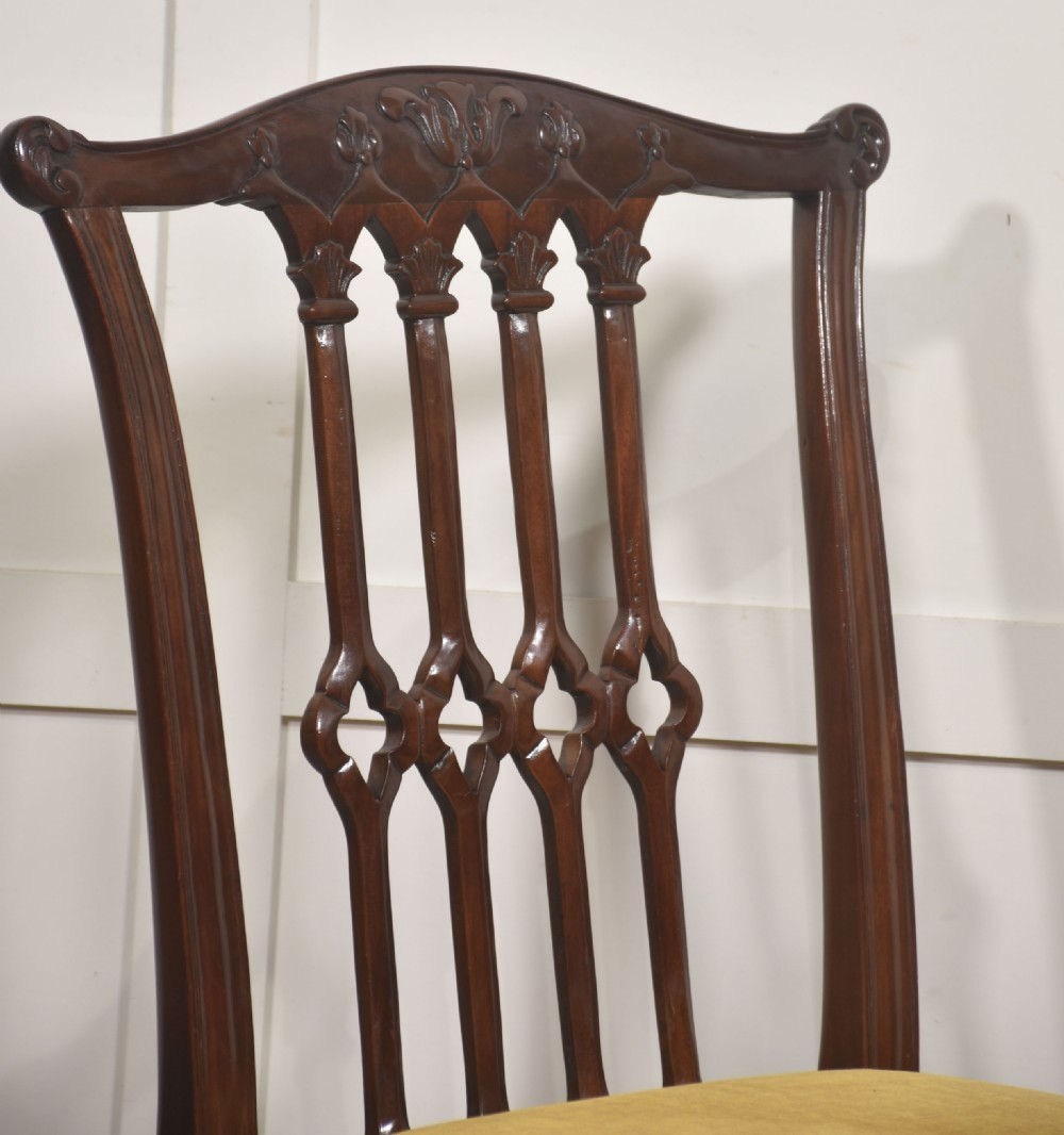 Set of four dark mahogany dining chairs featuring carved pierced splats, yellow velvet upholstered seats, and cabriole front legs with ball and claw feet. View VI