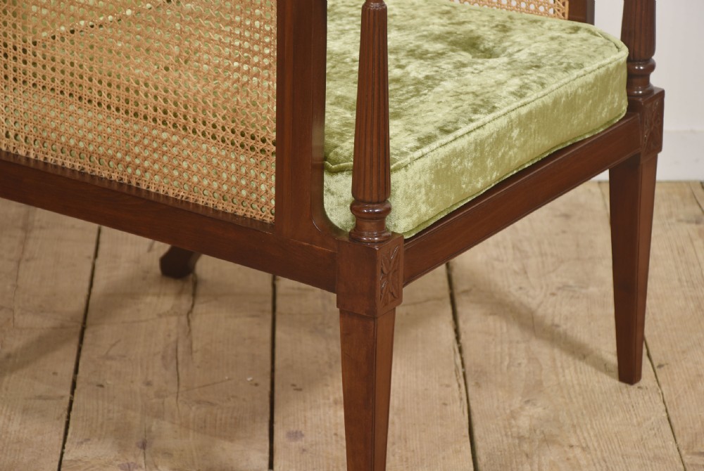 A mahogany bergere armchair with woven rattan cane side panels, turned front arm supports, and button-tufted sage green velvet cushions. View II