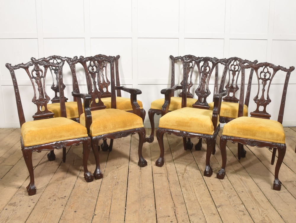 A set of eight dark mahogany dining chairs featuring elaborate pierced back splats, cabriole legs with ball and claw feet, and mustard yellow velvet upholstered seats.