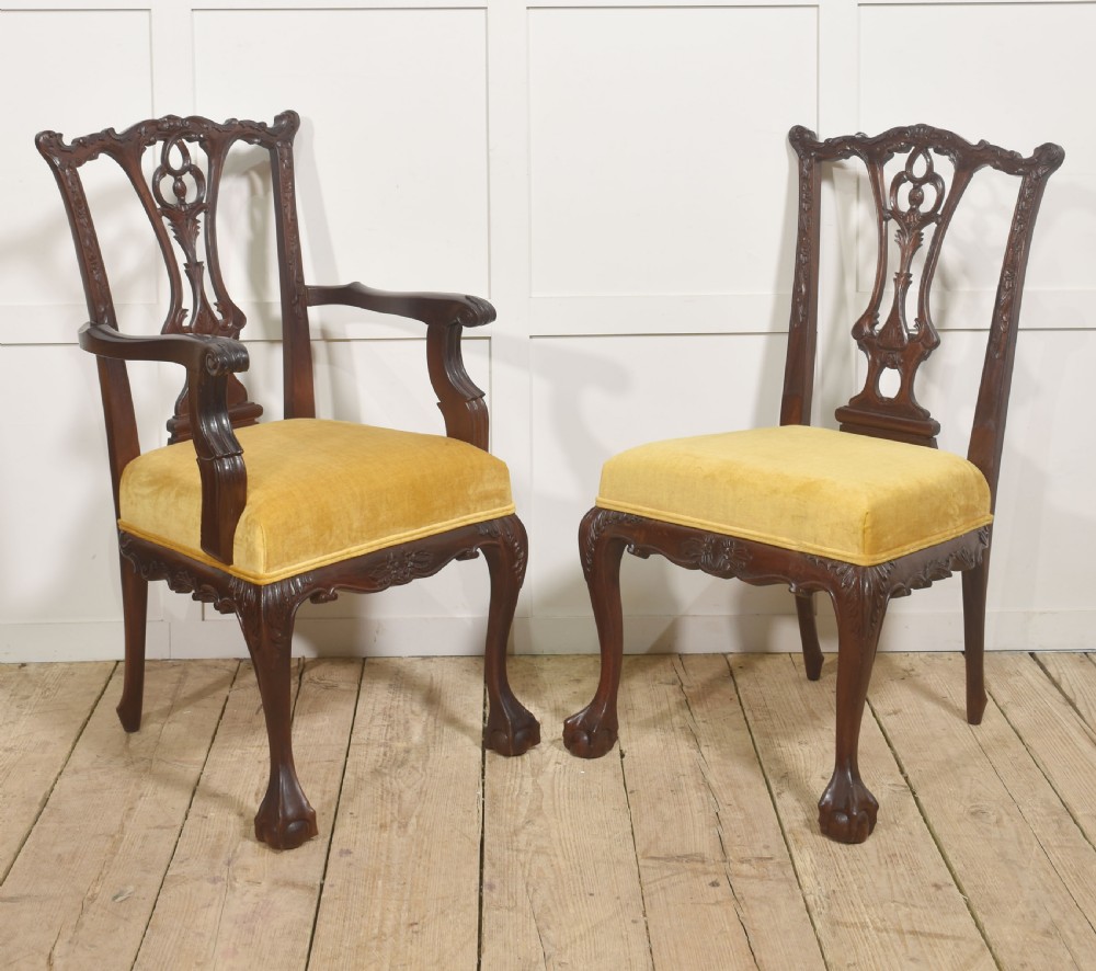 A set of eight dark mahogany dining chairs featuring elaborate pierced back splats, cabriole legs with ball and claw feet, and mustard yellow velvet upholstered seats. View X