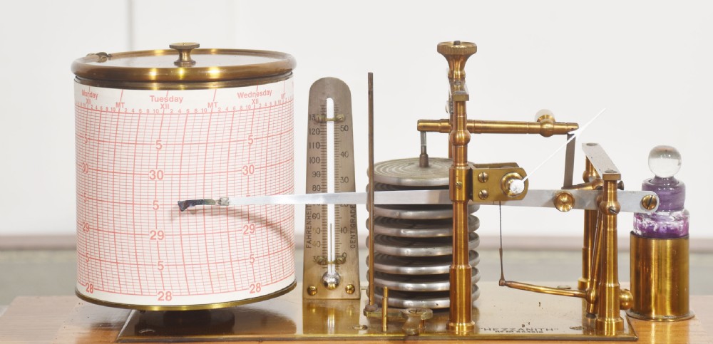 An Edwardian oak-cased barograph featuring bevelled glass panels, polished brass movement, paper chart drum, and floral Art Nouveau wood inlay along the base drawer and corner pillars. View VI