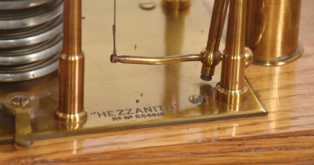 An Edwardian oak-cased barograph featuring bevelled glass panels, polished brass movement, paper chart drum, and floral Art Nouveau wood inlay along the base drawer and corner pillars. View IX