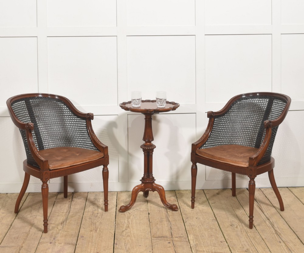 A pair of Regency style dark mahogany bergere armchairs featuring woven cane backs and tan leather buttoned seat cushions. View III