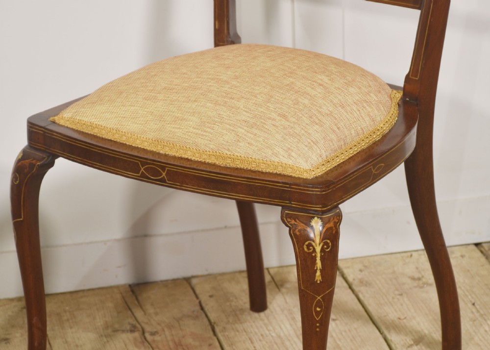 A pair of Edwardian inlaid mahogany side chairs with vase-shaped marquetry splats, cabriole front legs, and golden upholstered seats. View VI