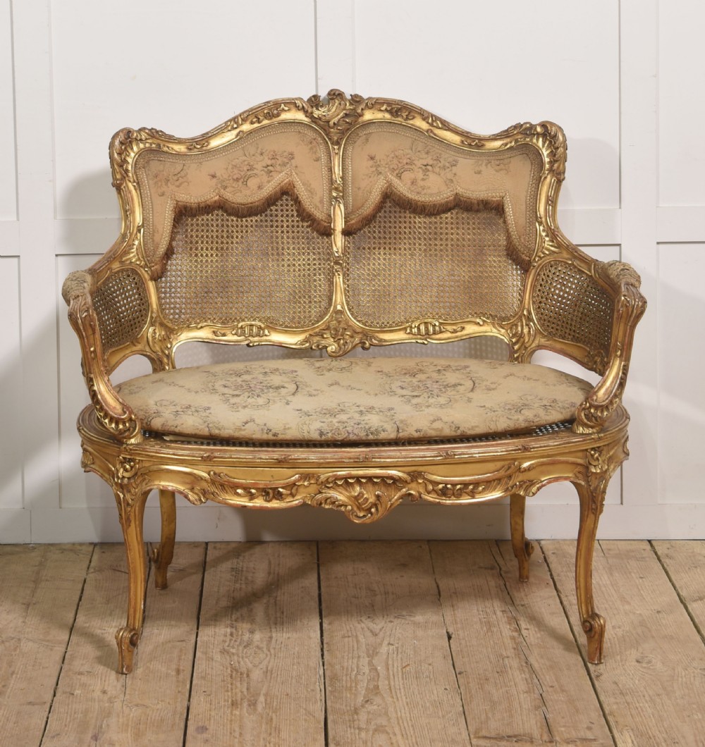 A French Louis XV style giltwood canape featuring a carved frame, caned back and sides, cabriole legs, and an upholstered seat cushion. View II