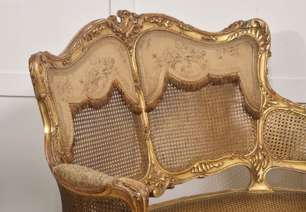 A French Louis XV style giltwood canape featuring a carved frame, caned back and sides, cabriole legs, and an upholstered seat cushion. View VII