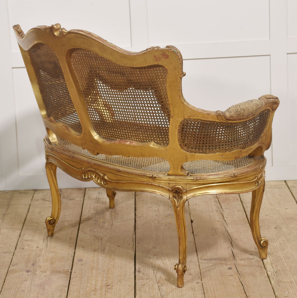 A French Louis XV style giltwood canape featuring a carved frame, caned back and sides, cabriole legs, and an upholstered seat cushion. View VIII