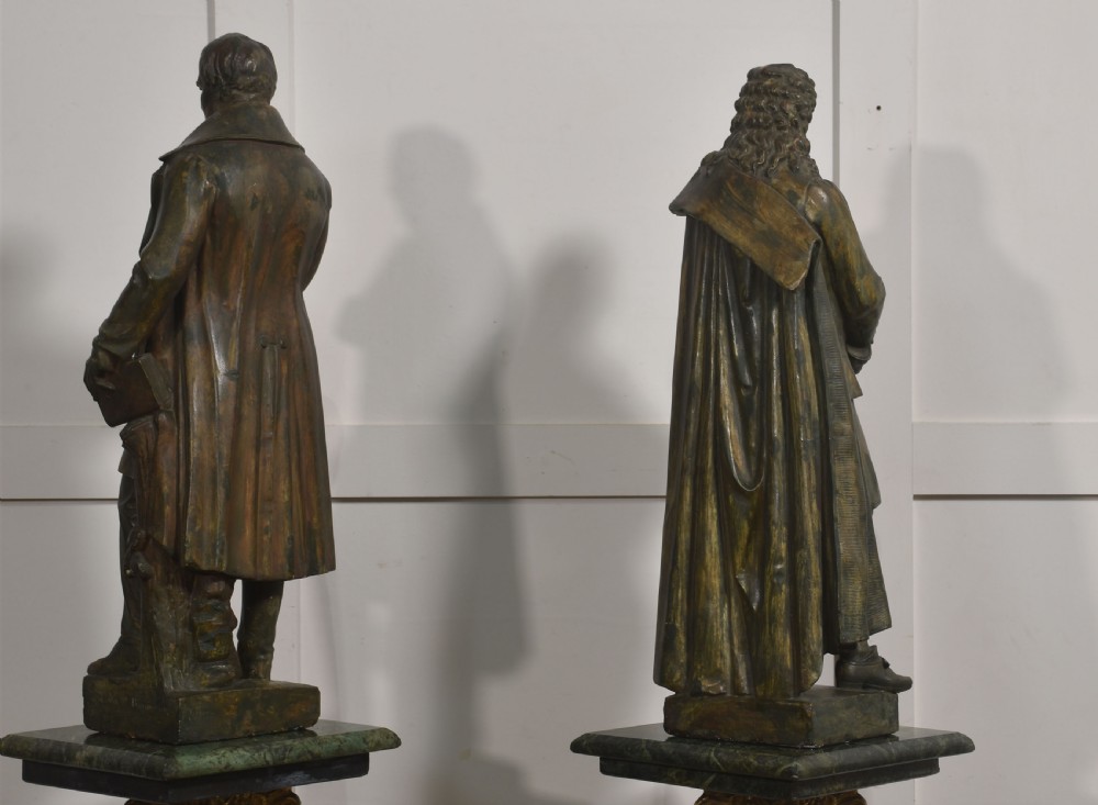 A pair of late nineteenth-century patinated chalkware statues depicting two standing male figures in historical attire on integral rectangular bases. View XII