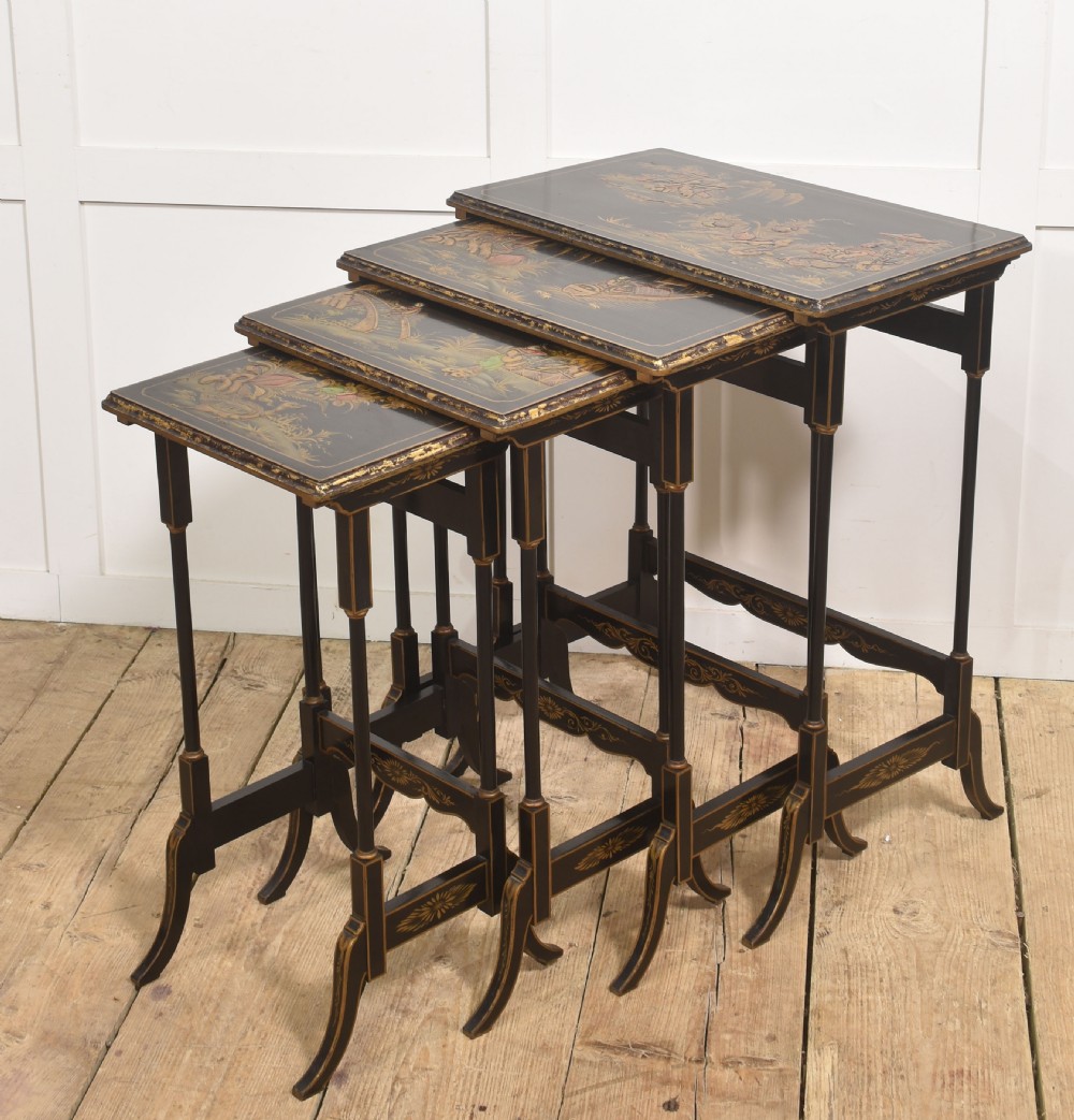 A graduating set of four black lacquered nesting tables decorated with gold Chinoiserie landscapes, slender turned legs, and curved stretchers.