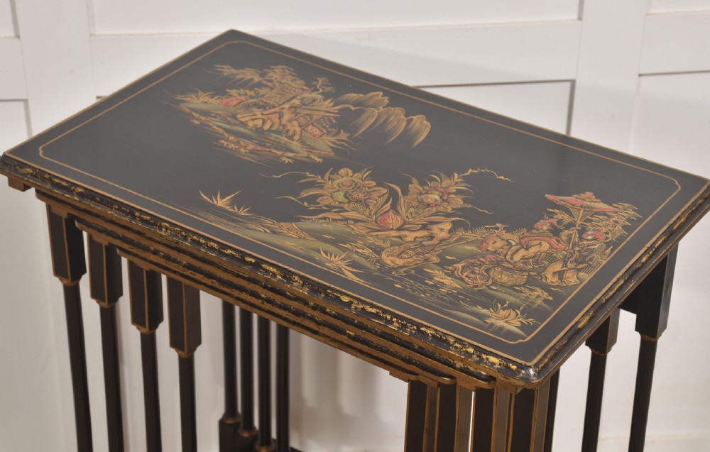 A graduating set of four black lacquered nesting tables decorated with gold Chinoiserie landscapes, slender turned legs, and curved stretchers. View IV