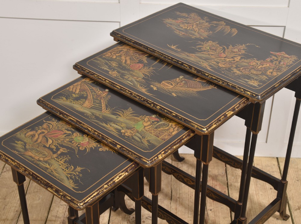 A graduating set of four black lacquered nesting tables decorated with gold Chinoiserie landscapes, slender turned legs, and curved stretchers. View V