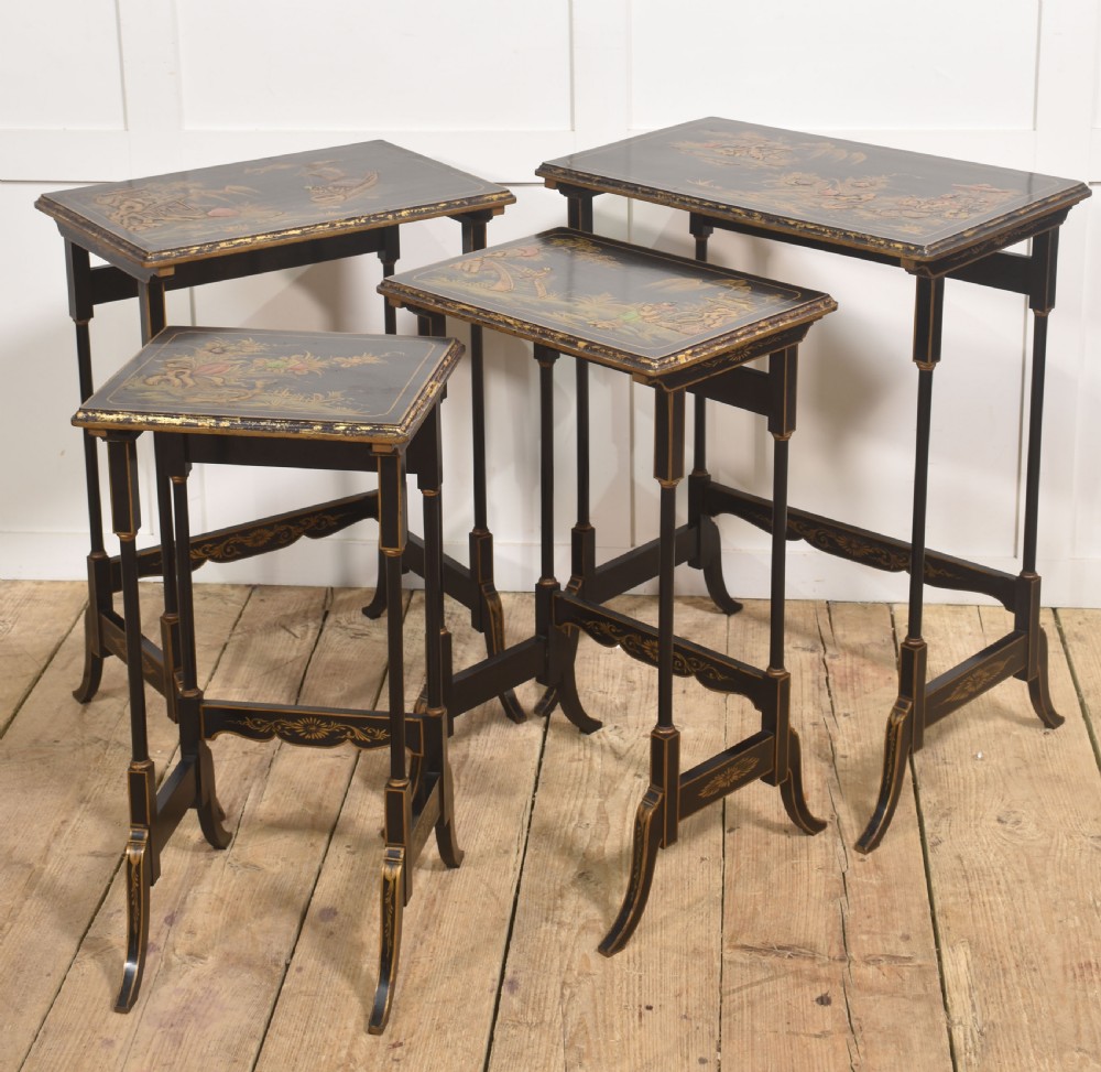 A graduating set of four black lacquered nesting tables decorated with gold Chinoiserie landscapes, slender turned legs, and curved stretchers. View VI