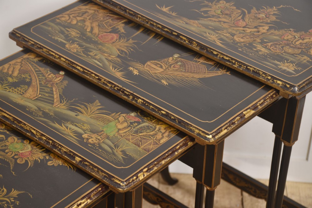 A graduating set of four black lacquered nesting tables decorated with gold Chinoiserie landscapes, slender turned legs, and curved stretchers. View VII