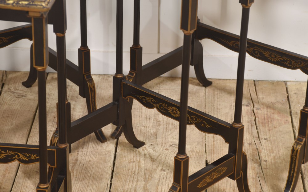A graduating set of four black lacquered nesting tables decorated with gold Chinoiserie landscapes, slender turned legs, and curved stretchers. View IX