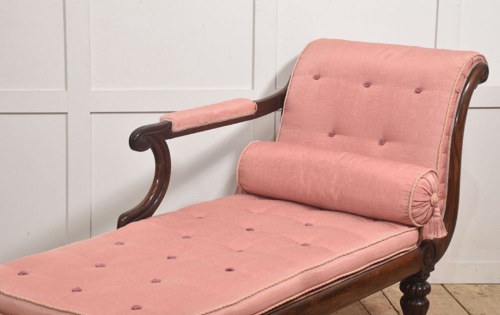 A William IV rosewood chaise longue upholstered in pink fabric with a matching bolster cushion and turned legs on brass castors. View V