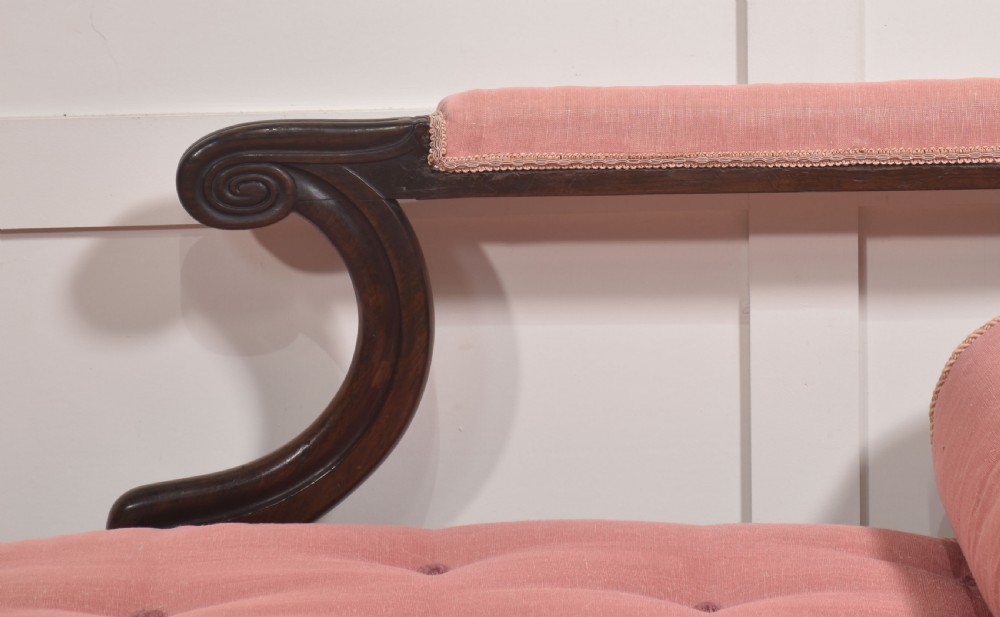 A William IV rosewood chaise longue upholstered in pink fabric with a matching bolster cushion and turned legs on brass castors. View VI