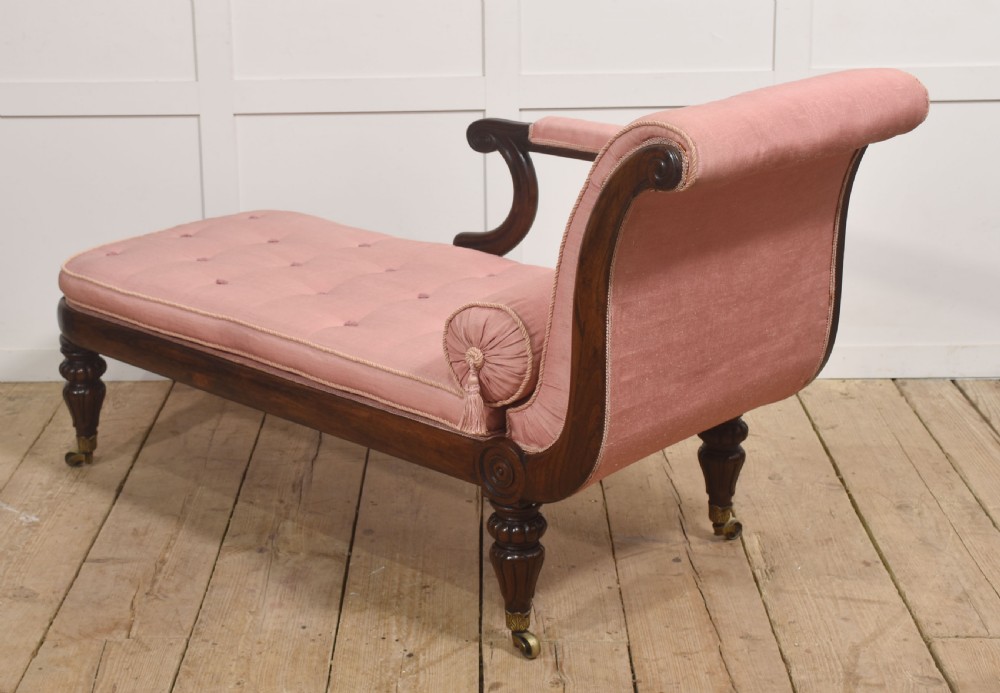 A William IV rosewood chaise longue upholstered in pink fabric with a matching bolster cushion and turned legs on brass castors. View VIII
