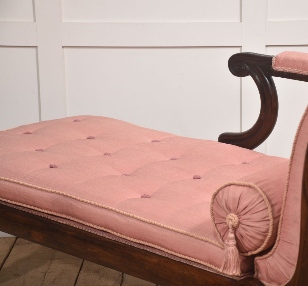 A William IV rosewood chaise longue upholstered in pink fabric with a matching bolster cushion and turned legs on brass castors. View IX