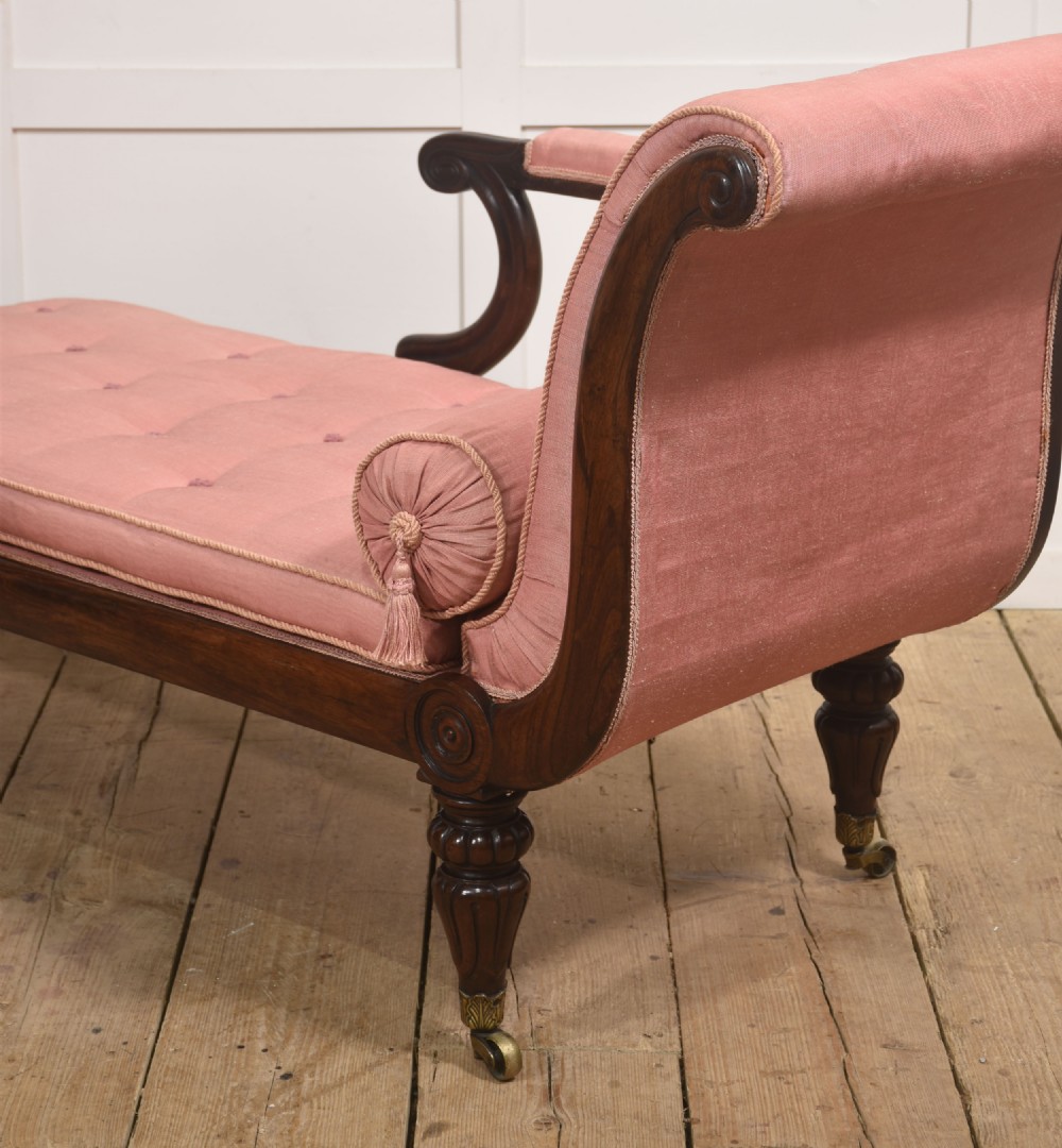 A William IV rosewood chaise longue upholstered in pink fabric with a matching bolster cushion and turned legs on brass castors. View X