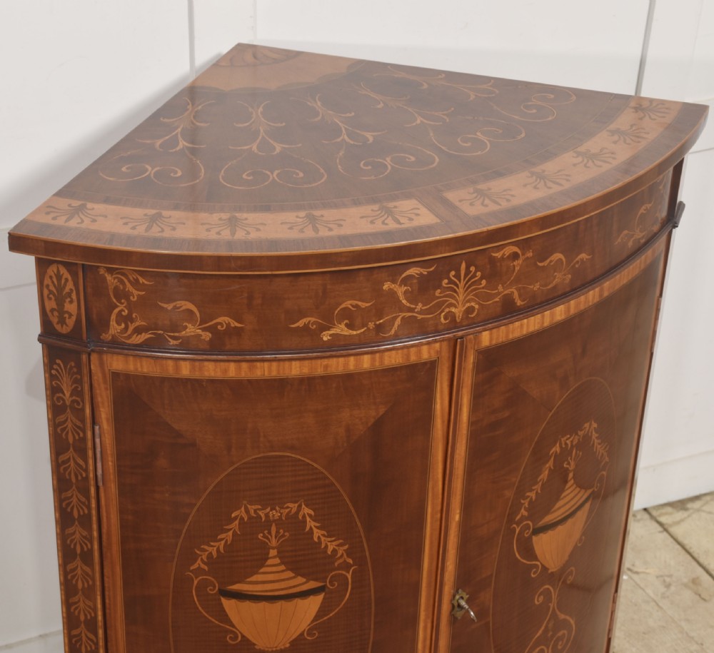 A floor-standing Sheraton Revival bow-front mahogany corner cabinet with satinwood neoclassical urn marquetry on twin doors. View VI
