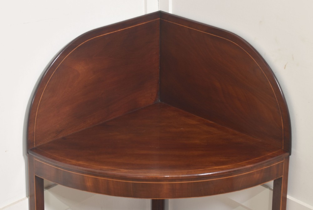 An antique Georgian mahogany corner washstand with boxwood line inlay, a curved splashback, a lower drawer, and out-swept legs. View III