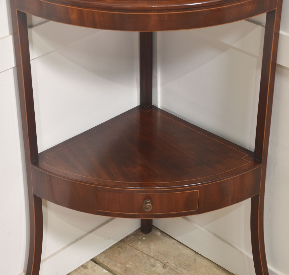 An antique Georgian mahogany corner washstand with boxwood line inlay, a curved splashback, a lower drawer, and out-swept legs. View IV