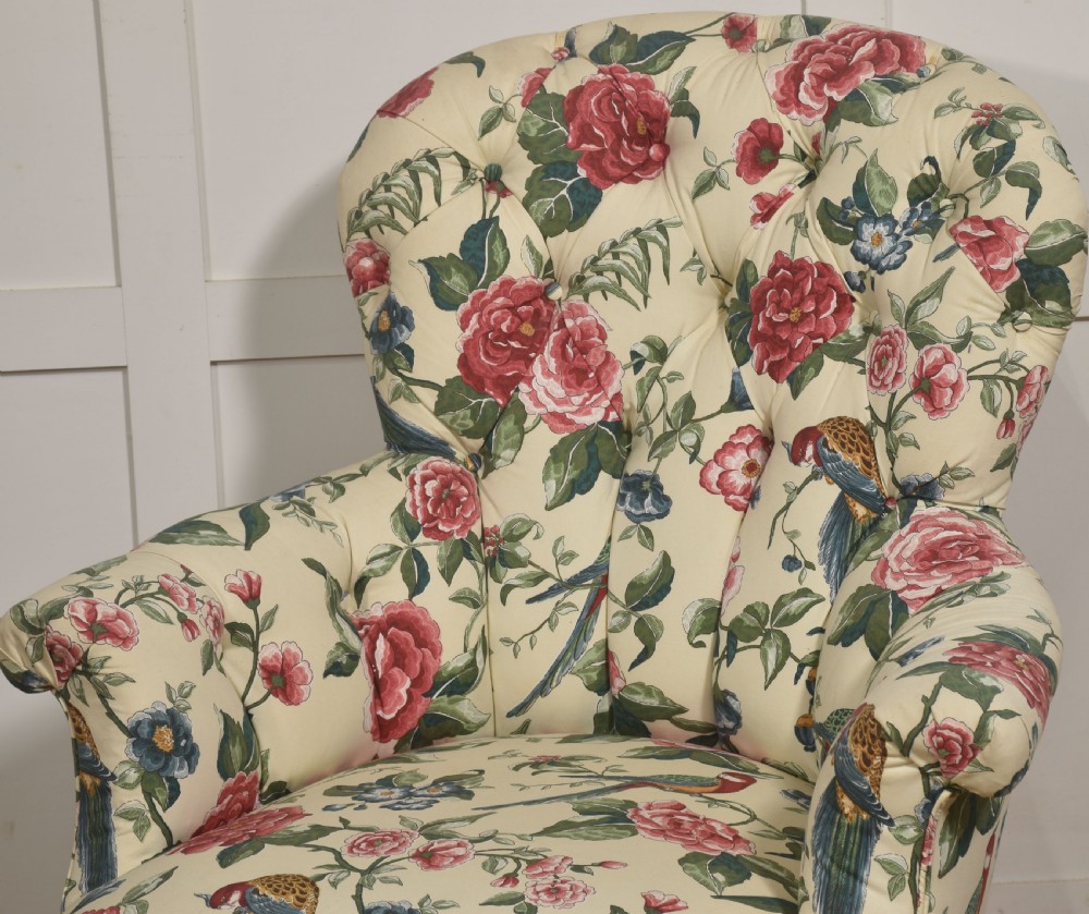 A late nineteenth-century Victorian armchair upholstered in cream floral and bird patterned fabric featuring a button-backed backrest and a pleated bottom skirt. View III