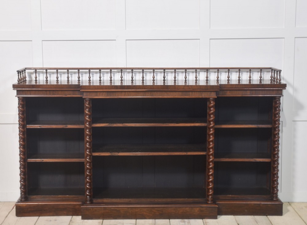 A large Victorian rosewood breakfront open bookcase featuring three shelf sections, carved barley twist columns, and a spindle gallery along the top edge. View III