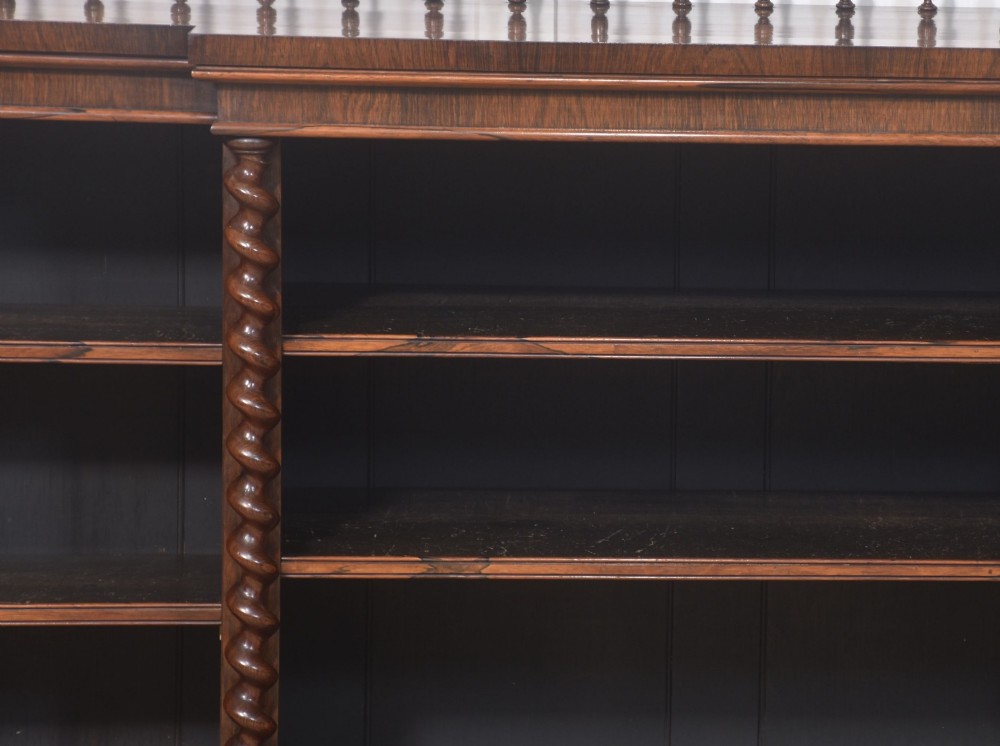 A large Victorian rosewood breakfront open bookcase featuring three shelf sections, carved barley twist columns, and a spindle gallery along the top edge. View V