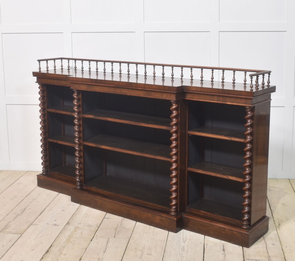 A large Victorian rosewood breakfront open bookcase featuring three shelf sections, carved barley twist columns, and a spindle gallery along the top edge. View VIII