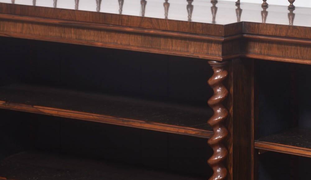 A large Victorian rosewood breakfront open bookcase featuring three shelf sections, carved barley twist columns, and a spindle gallery along the top edge. View IX