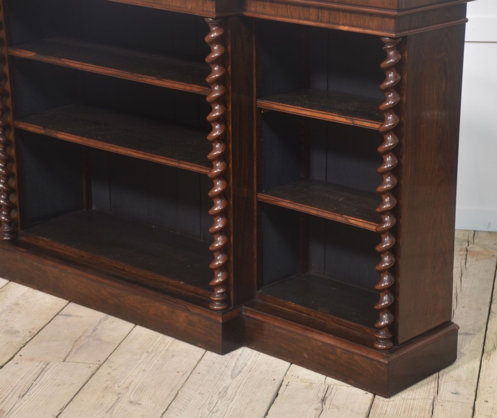 A large Victorian rosewood breakfront open bookcase featuring three shelf sections, carved barley twist columns, and a spindle gallery along the top edge. View XI