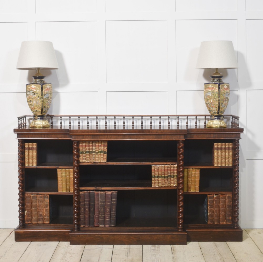 A large Victorian rosewood breakfront open bookcase featuring three shelf sections, carved barley twist columns, and a spindle gallery along the top edge. View XII