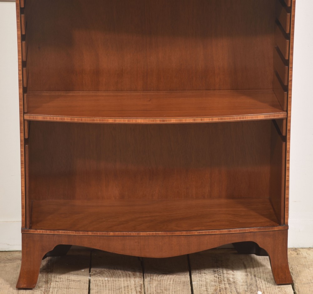 A tall, narrow mahogany open bookcase featuring five shelves, decorative inlay on the top frieze, and shaped bracket feet. View VII