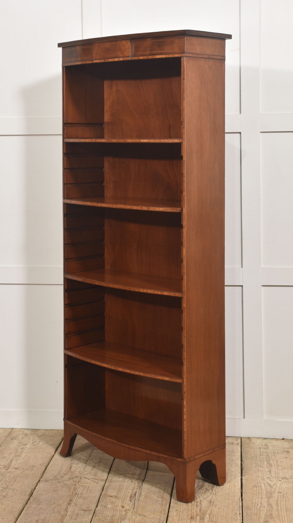 A tall, narrow mahogany open bookcase featuring five shelves, decorative inlay on the top frieze, and shaped bracket feet. View VIII
