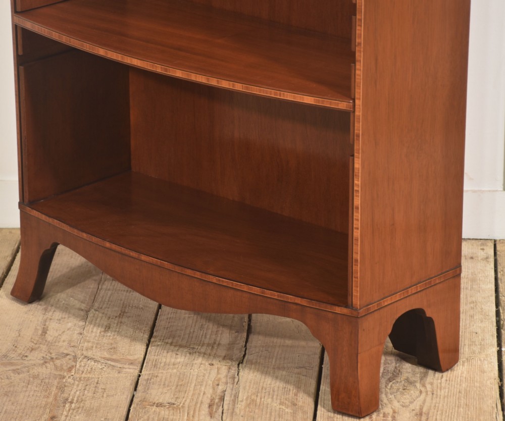A tall, narrow mahogany open bookcase featuring five shelves, decorative inlay on the top frieze, and shaped bracket feet. View IX