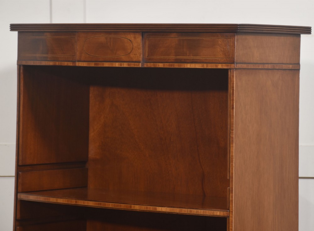 A tall, narrow mahogany open bookcase featuring five shelves, decorative inlay on the top frieze, and shaped bracket feet. View X