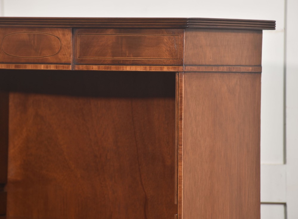 A tall, narrow mahogany open bookcase featuring five shelves, decorative inlay on the top frieze, and shaped bracket feet. View XI