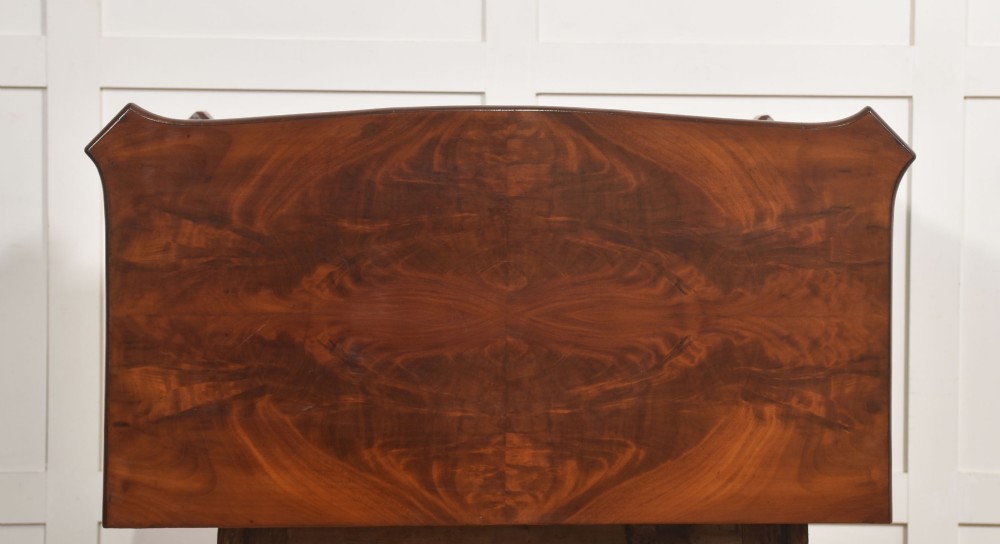 A 19th-century flame mahogany side cabinet with a single top drawer above two panelled cupboard doors with brass keyhole escutcheons. View XII