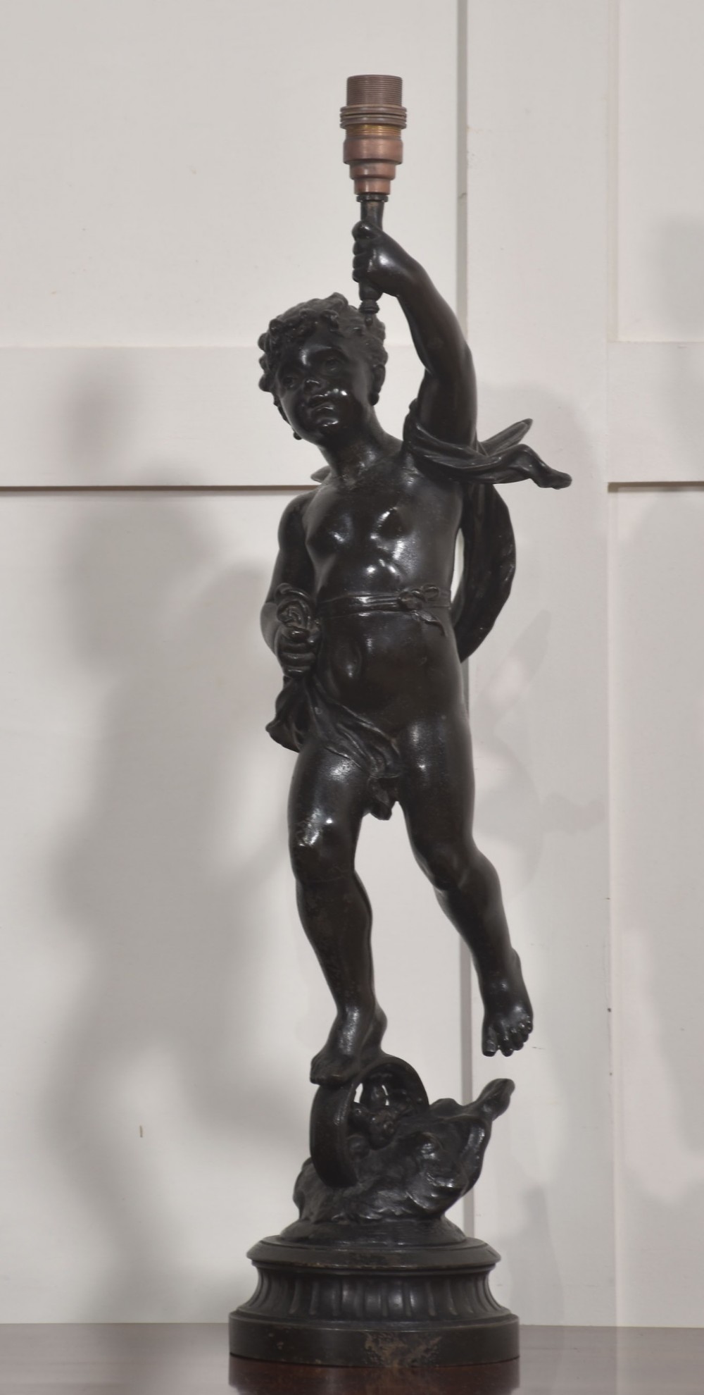 A 19th-century patinated dark bronze table lamp crafted in the shape of a standing cherub holding a torch socket on a moulded base.