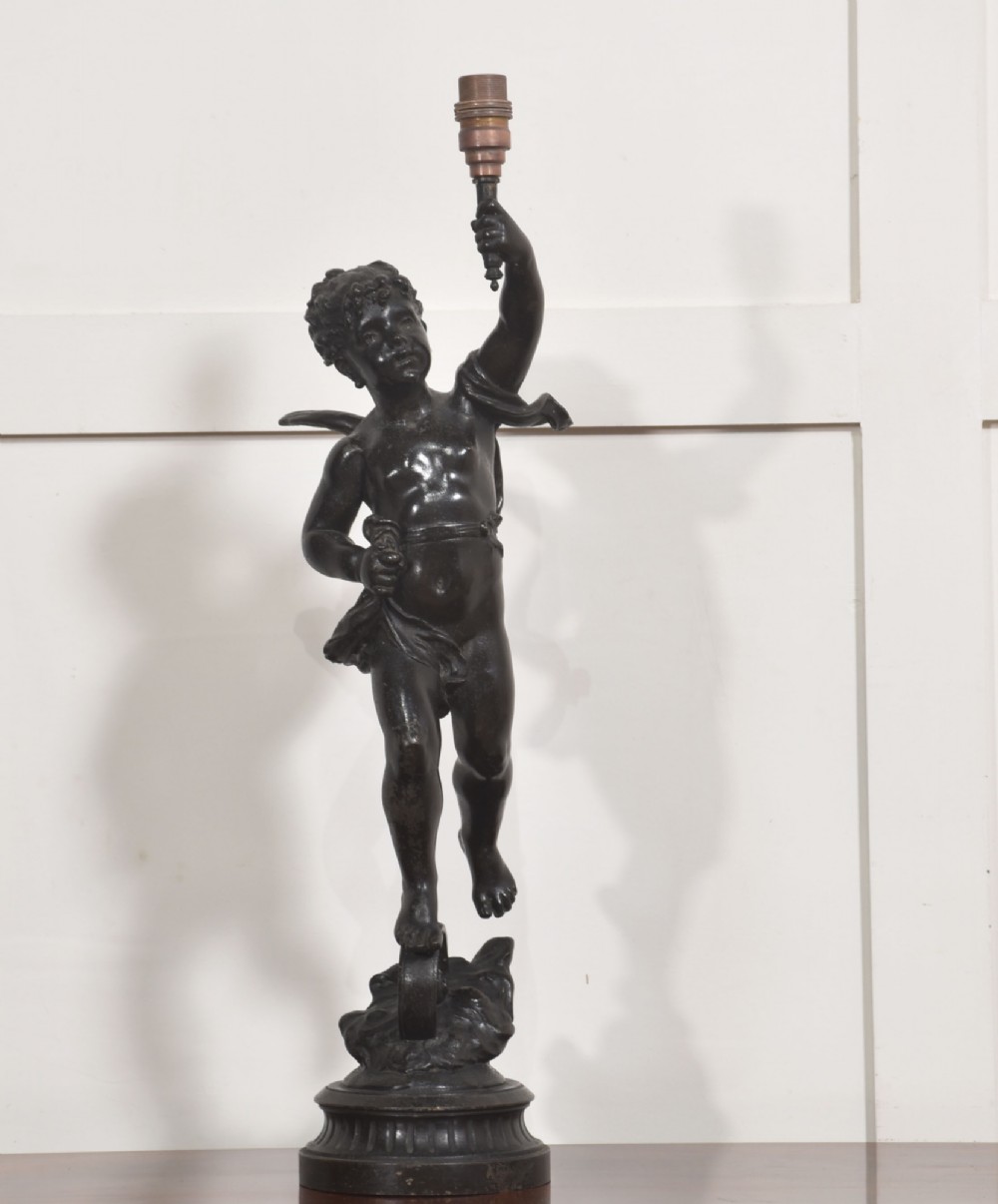 A 19th-century patinated dark bronze table lamp crafted in the shape of a standing cherub holding a torch socket on a moulded base. View II