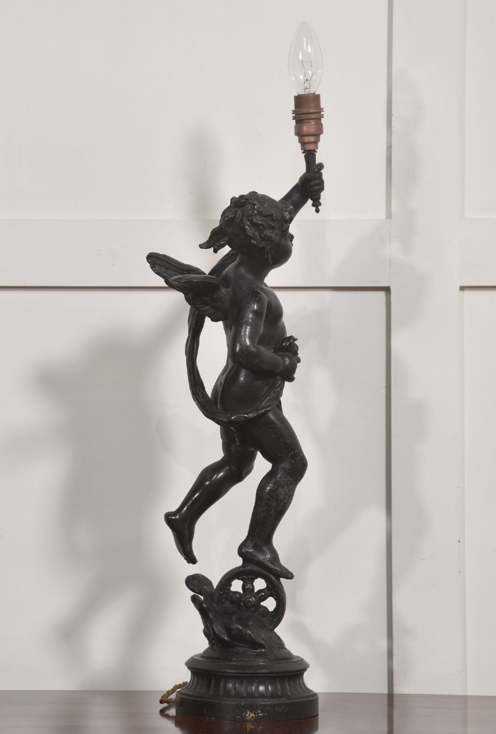A 19th-century patinated dark bronze table lamp crafted in the shape of a standing cherub holding a torch socket on a moulded base. View VI