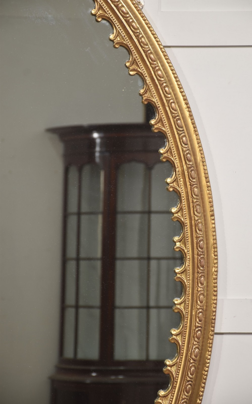 A large 19th-century oval wall mirror featuring a gilded frame with top shell cresting and scalloped inner detailing. View IV