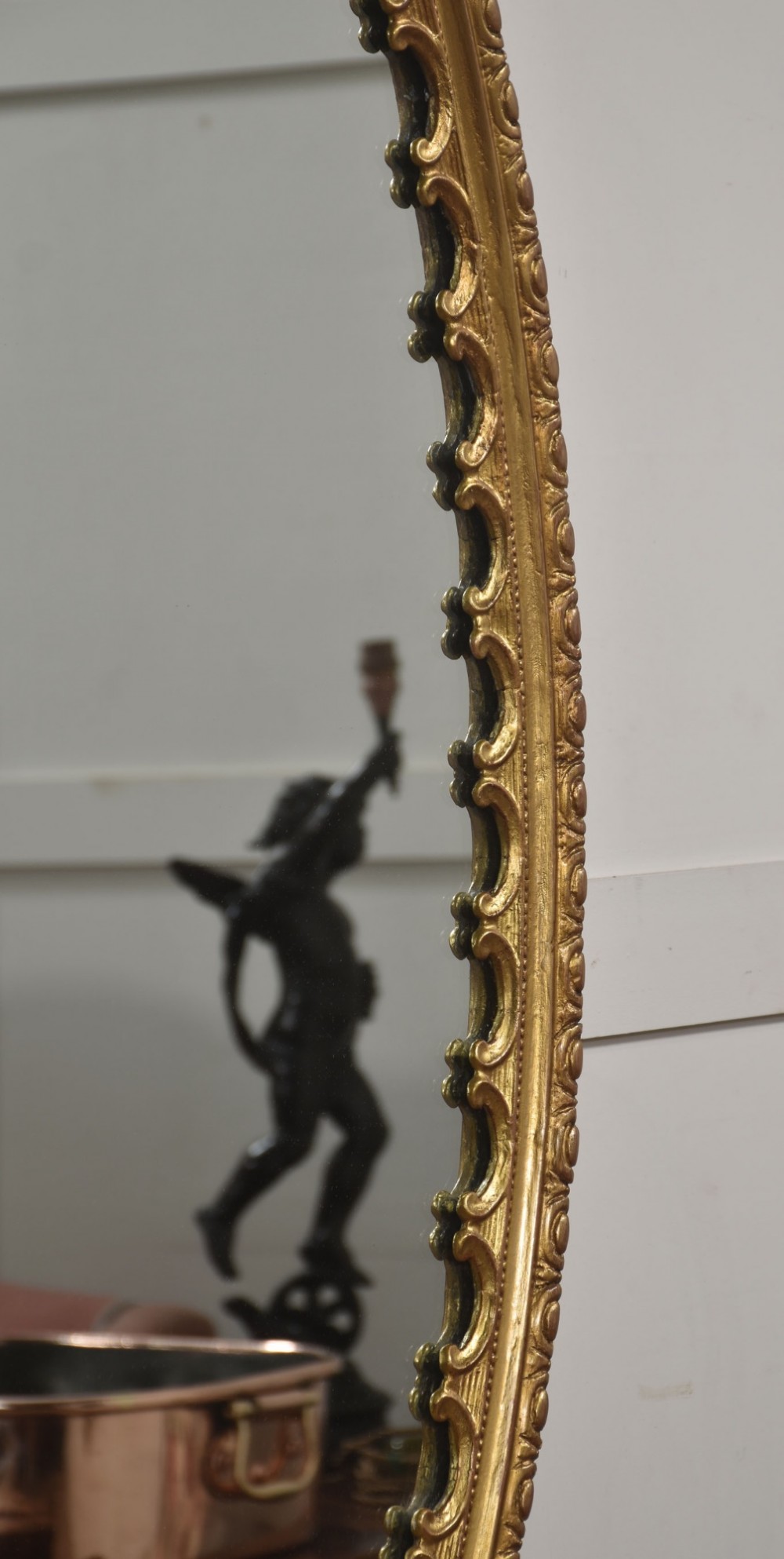 A large 19th-century oval wall mirror featuring a gilded frame with top shell cresting and scalloped inner detailing. View VII