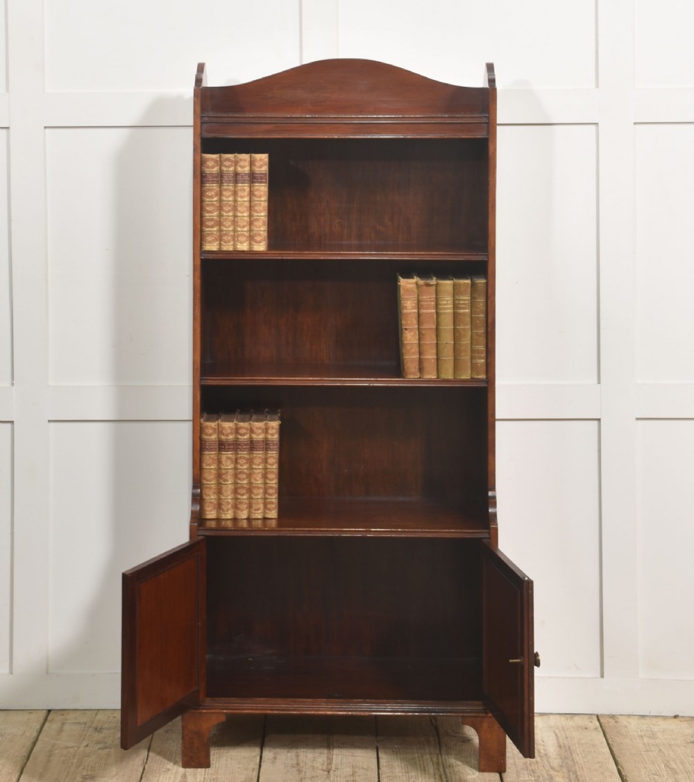 A tall Georgian style mahogany open bookcase featuring three open shelves, a contoured upper gallery, and a lower two-door panelled cupboard raised on bracket feet. View II