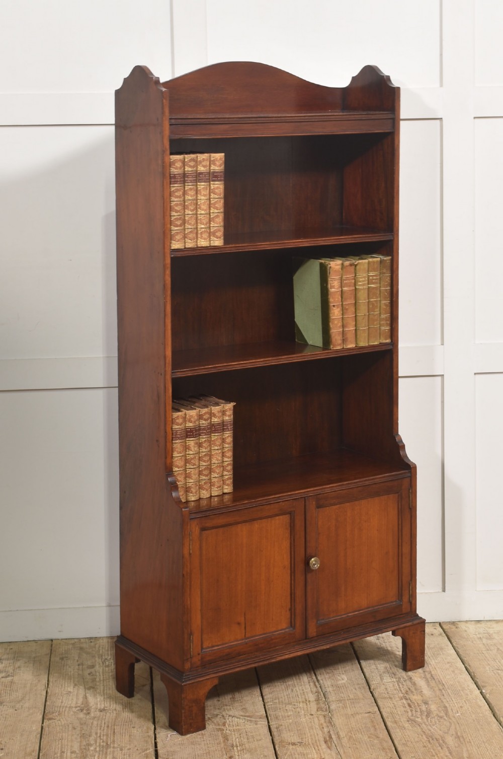 A tall Georgian style mahogany open bookcase featuring three open shelves, a contoured upper gallery, and a lower two-door panelled cupboard raised on bracket feet. View III