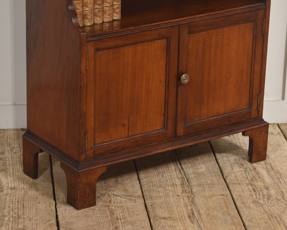 A tall Georgian style mahogany open bookcase featuring three open shelves, a contoured upper gallery, and a lower two-door panelled cupboard raised on bracket feet. View IV
