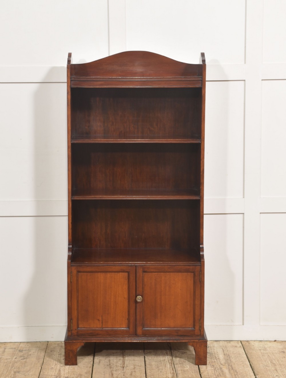 A tall Georgian style mahogany open bookcase featuring three open shelves, a contoured upper gallery, and a lower two-door panelled cupboard raised on bracket feet. View VIII