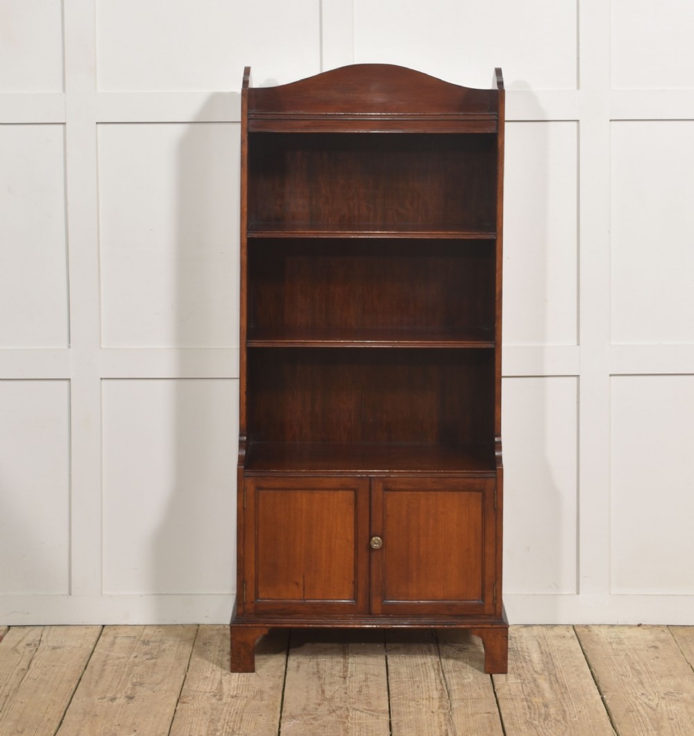 A tall Georgian style mahogany open bookcase featuring three open shelves, a contoured upper gallery, and a lower two-door panelled cupboard raised on bracket feet. View IX